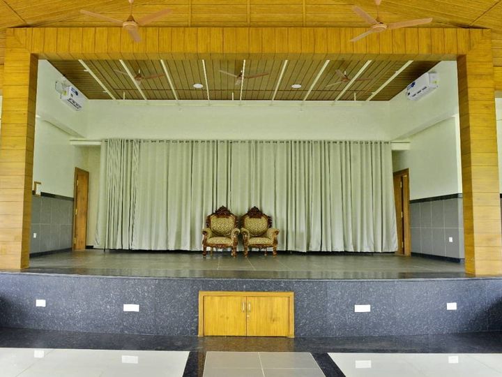 Stage with white curtains and two carved chairs, framed in wood