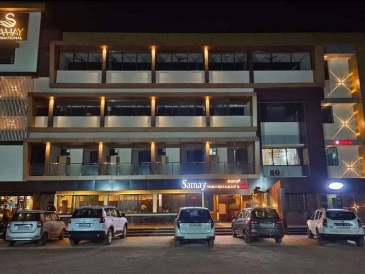 The hotel lit up at night, restaurant lights on the ground floor and cars parked in front