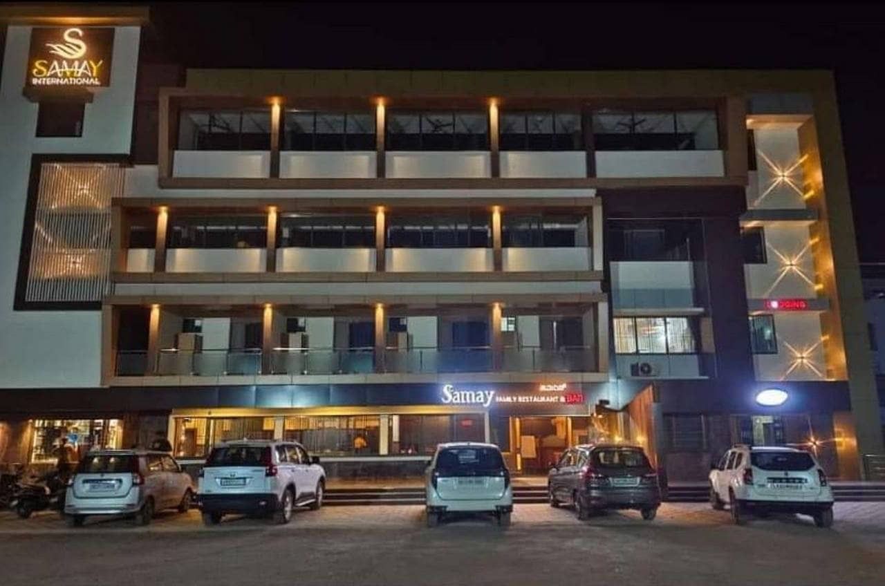 The hotel lit up at night, restaurant lights on the ground floor and cars parked in front