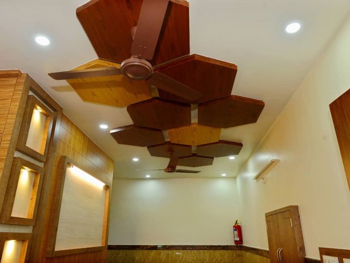 Lobby with wood panelling, lit wall niches and a carved wooden ceiling around the fan