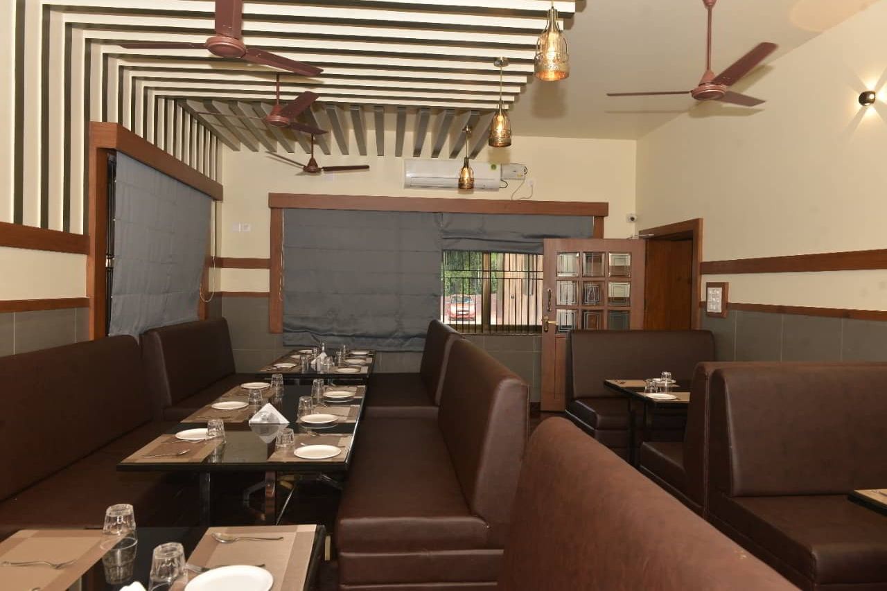Restaurant dining room with brown booths and tables laid with plates and glasses