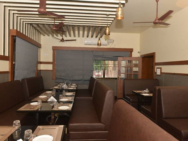 Restaurant dining room with brown booths and tables laid with plates and glasses