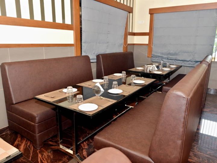 Restaurant tables with brown sofa seating beside windows with blinds
