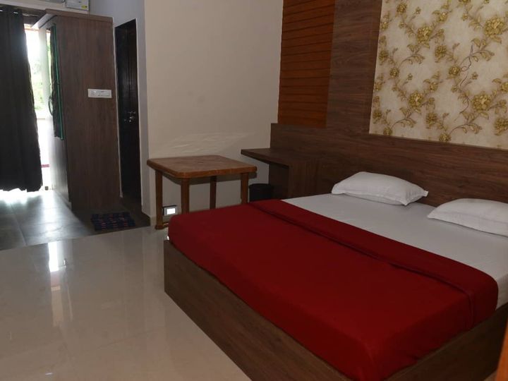 Double bed with a red bedspread, a wooden headboard and a patterned feature wall