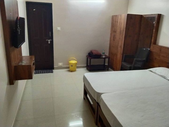 Room with two single beds, a wall-mounted TV, a wardrobe and a chair